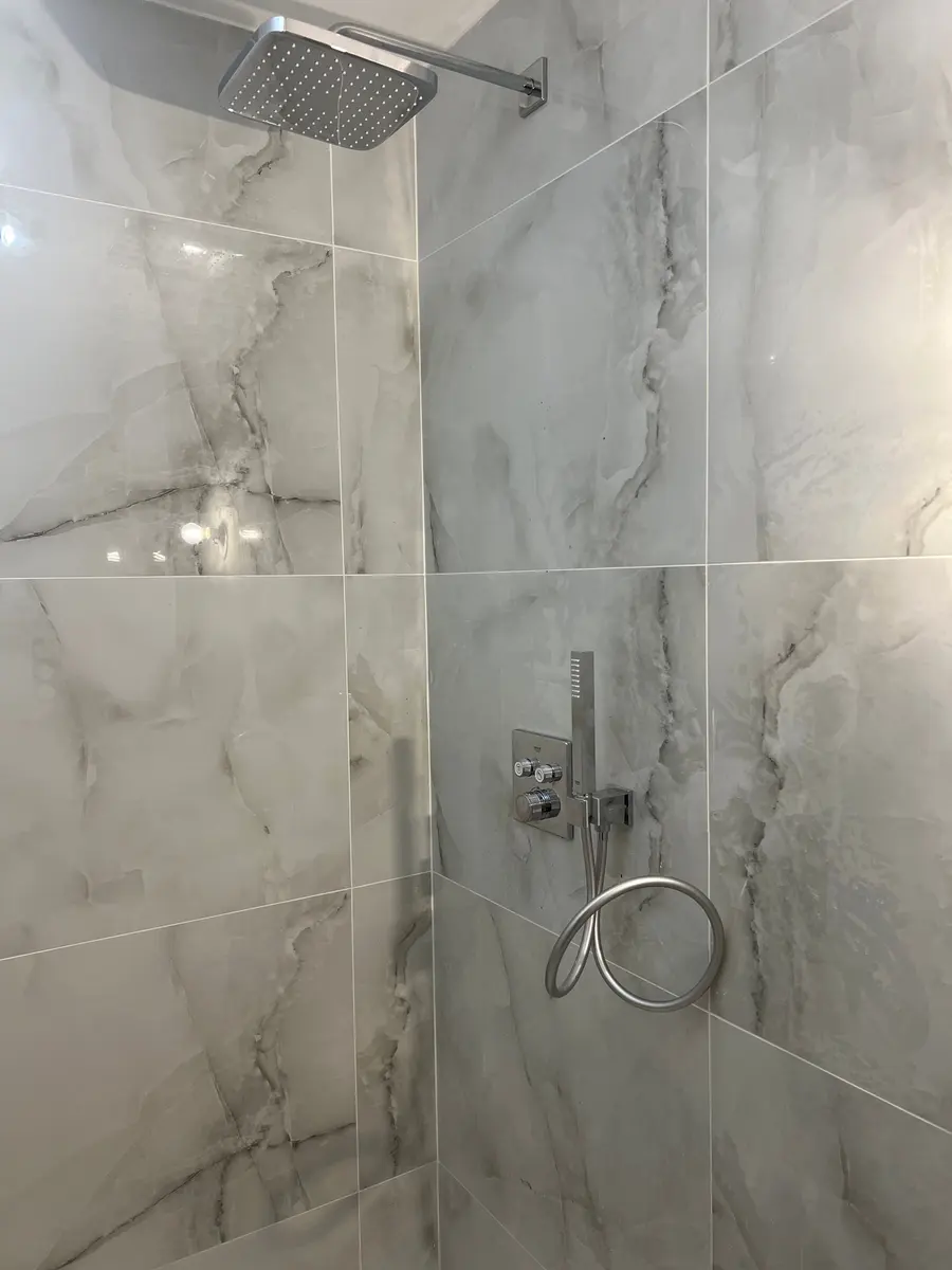 Mitigeur encastré dans une douche en carrelage marbre