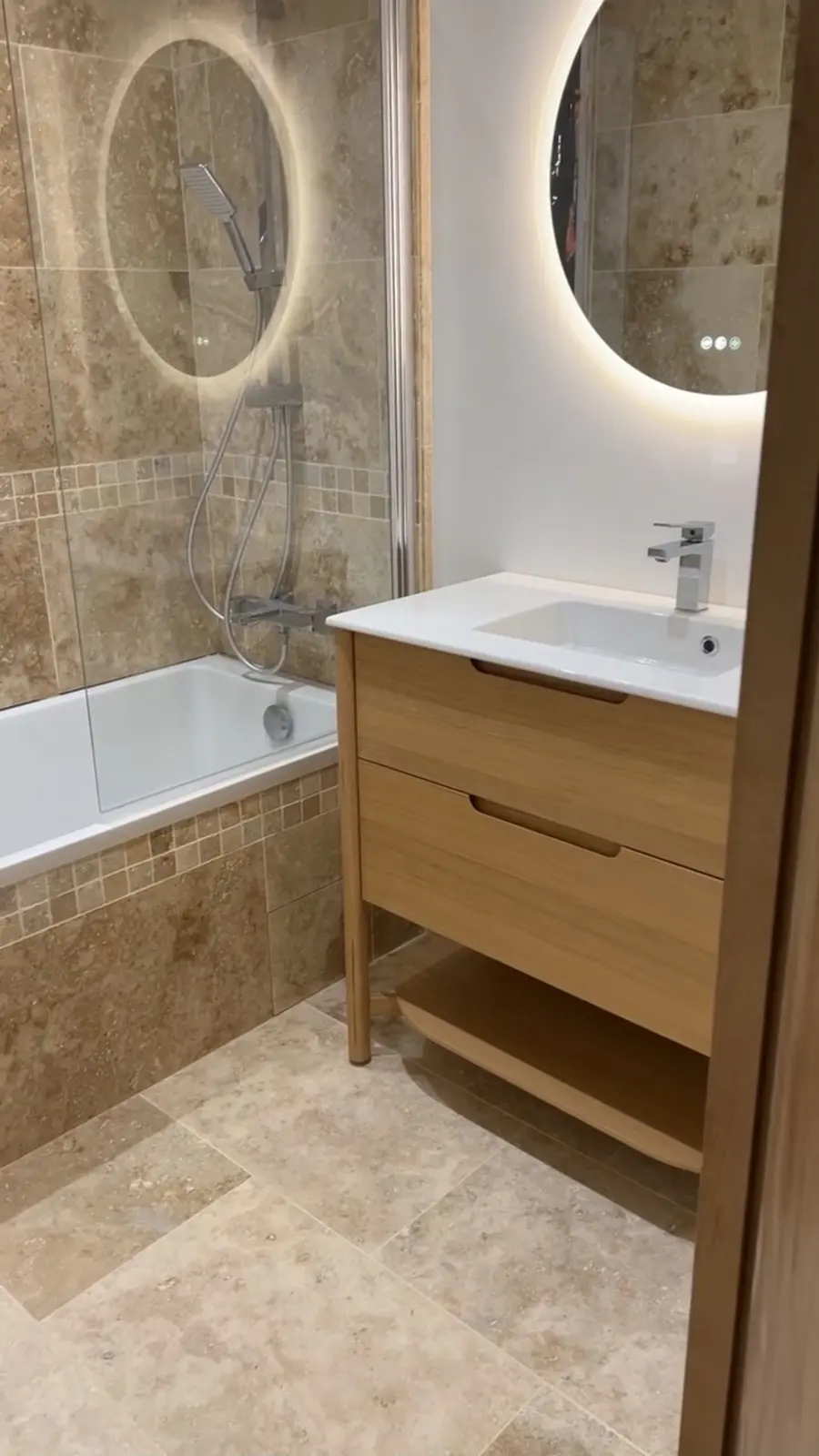 Salle de bain rénovée avec baignoire, meuble vasque en bois et miroirs LED