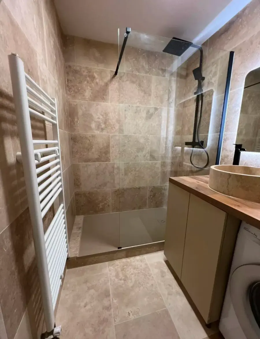 Salle de bain rénovée avec douche à l'italienne et carrelage travertin